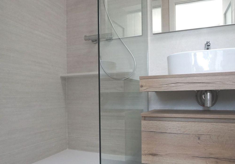Baño reformado con plato de ducha a ras de suelo y mueble de madera